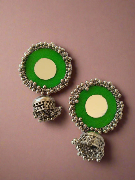 Light green round jhumka earrings with silver beads on white backdrop