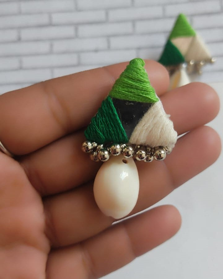 Palm holding triangular studs earrings in green with a sea shell at bottom