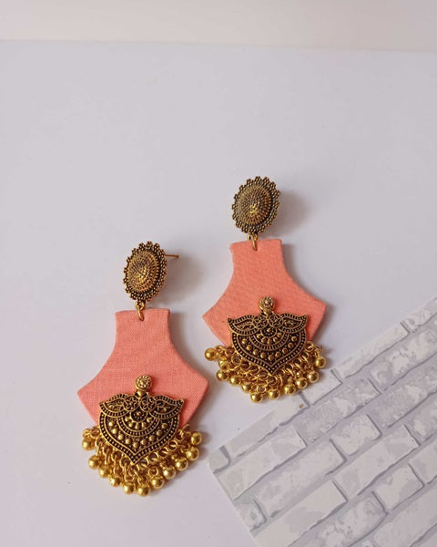 peach pink earrings with golden charm at bottom on white background