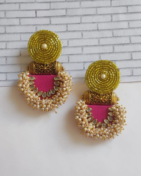 Yellow and pink with golden beads jhumka earrings on white grey backdrop