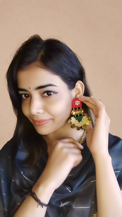 Indian girl smiling wearing green and red jhumka earrings with golden work and details