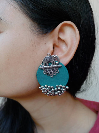 Close up of an ear of a girl wearing sea green studs earrings with elephant charm and silver beads