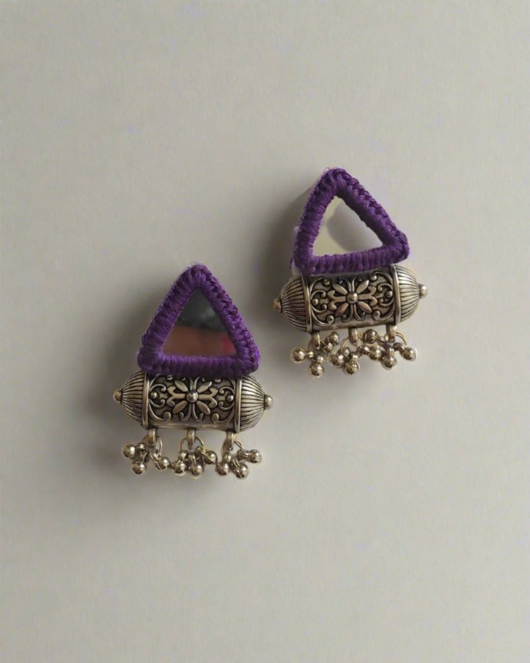 Triangular purple and silver mirror studs jhumka earrings on white grey backdrop