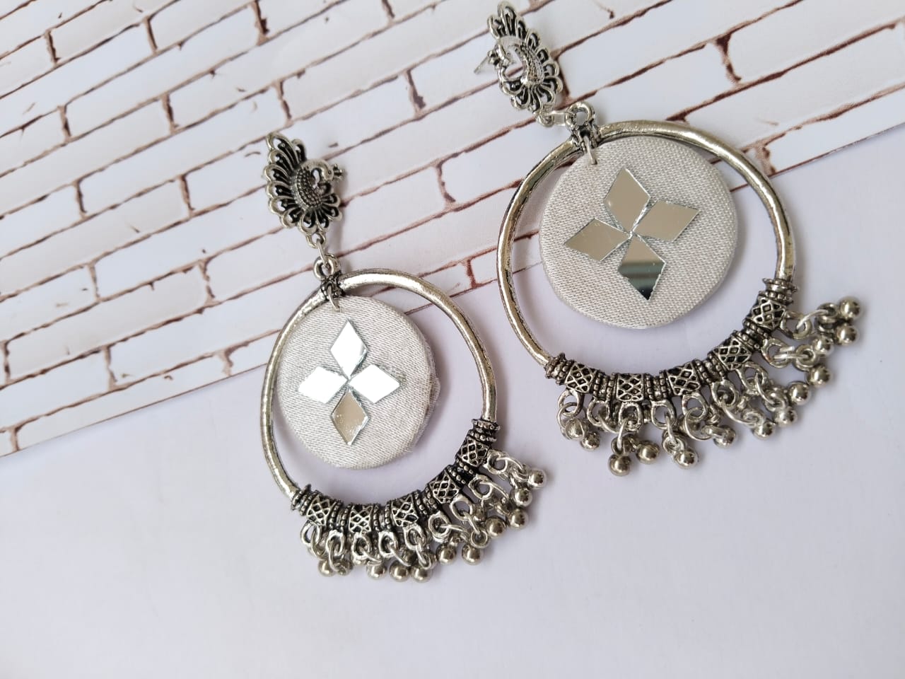 White jhumka earrings with bali style silver hoop and ghungroos on white grey backdrop