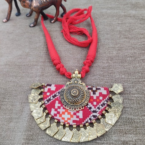 Red patola print necklace with golden details on brown backdrop