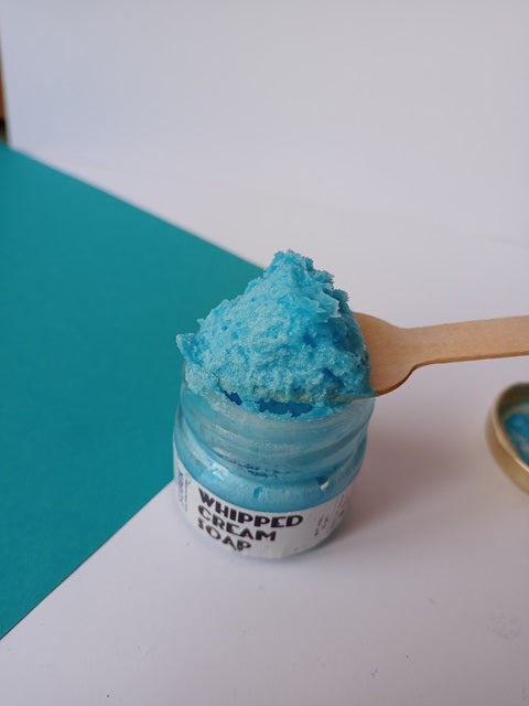 Mini glass jar with blue whipped cream soap on a wooden spoon