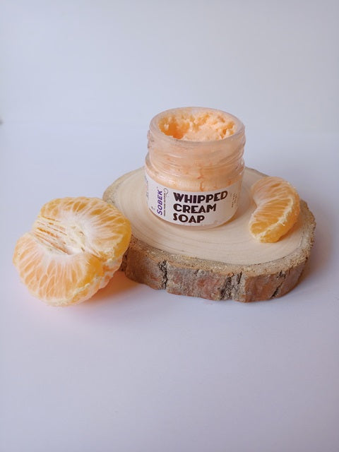 Orange minia glass jar with whipped cream soap and oranges around it