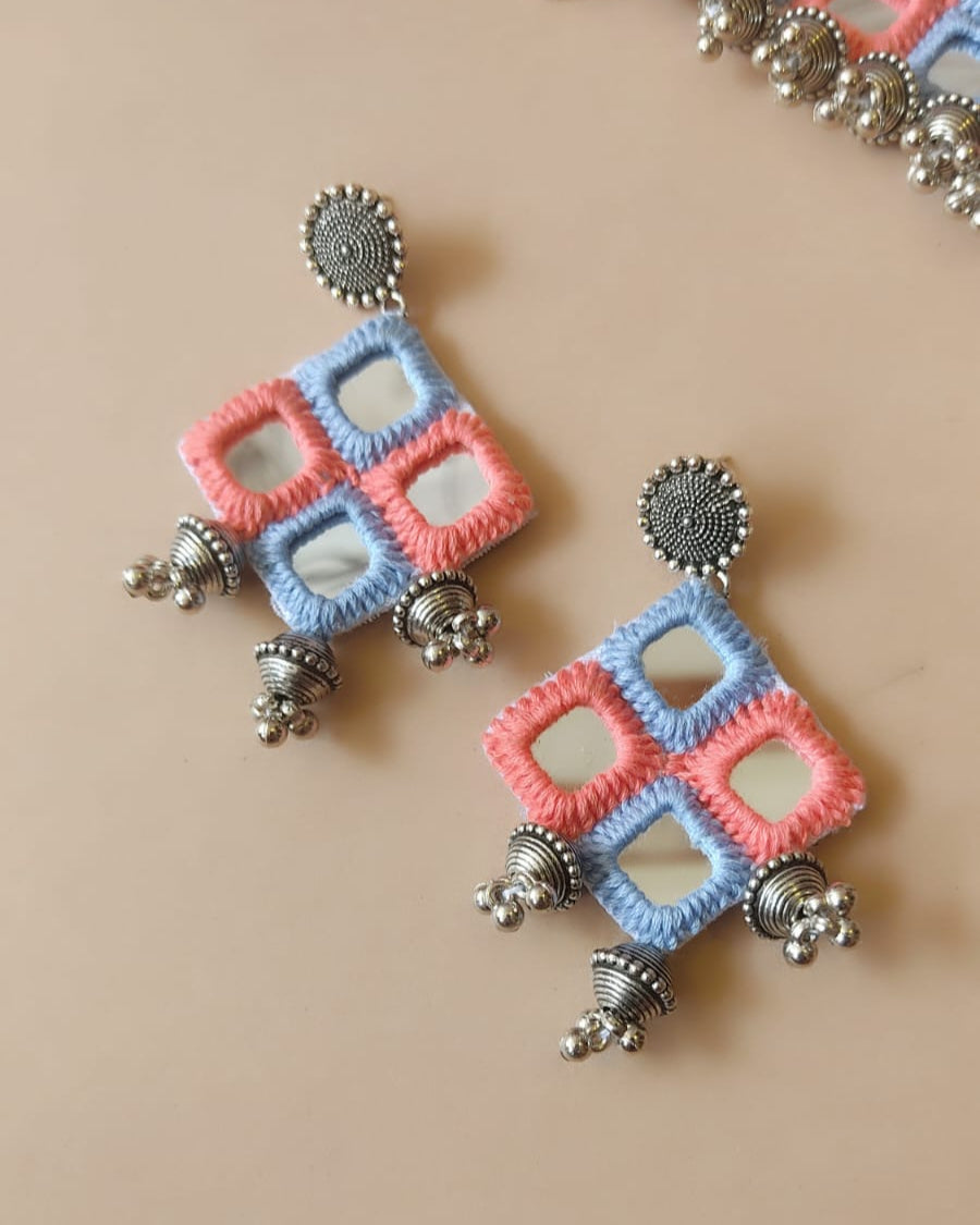 Pair of earrings with geometric design on a beige background