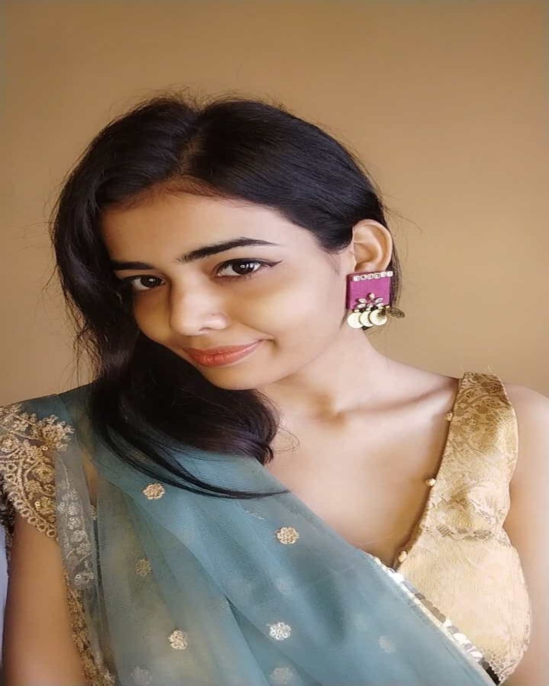 Indian girl smiling wearing saree and purple square earrings with kundan work