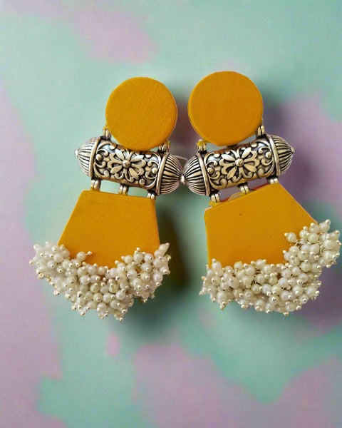 Yellow fabric earrings with silver charm and white beads at bottom