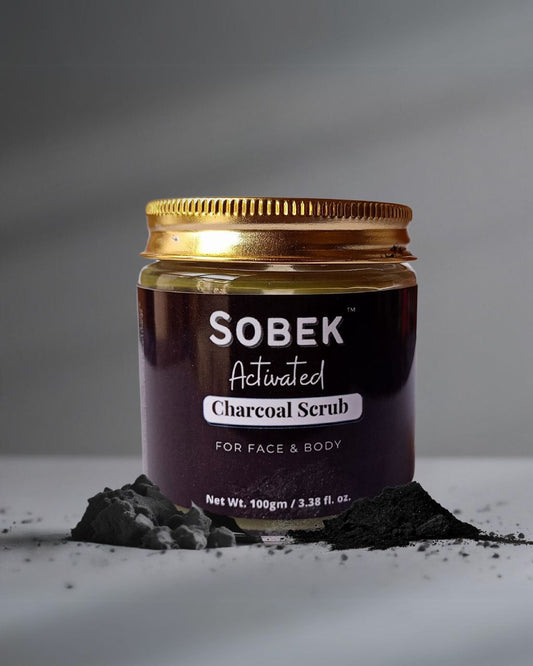Sobek naturals charcoal face and body scrub on grey backdrop with charcoal powder around