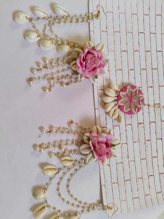 Rose pink tika and earrings set with white sea shells and roses on white and grey backdrop