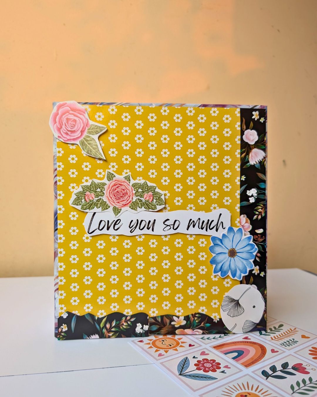 Handmade scrapbook with yellow floral cover, decorated with paper flowers and ‘Love you so much’ message – Rainvas personalized gifting