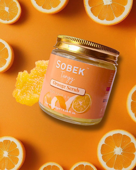 Sobek naturals orange face and body scrub in a glass jar with orange slices around it