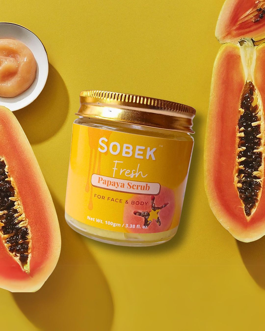 Sobek naturals papaya face and body scrub in a glass jar with papaya slices around it