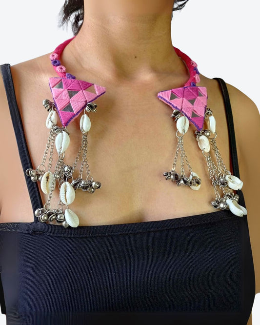 A person wearing a pink and silver mirror set with a necklace and a pair of earrings, featuring kundan embellishments and a friction back.