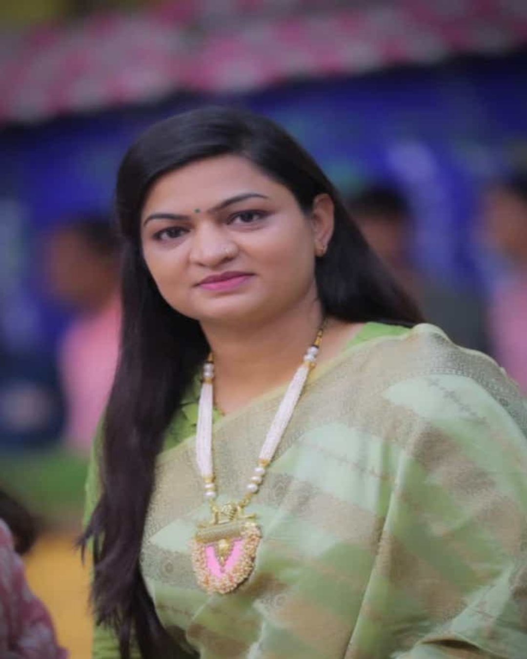 Indian woman in green saree wearing baby pink long necklace with white beads chain