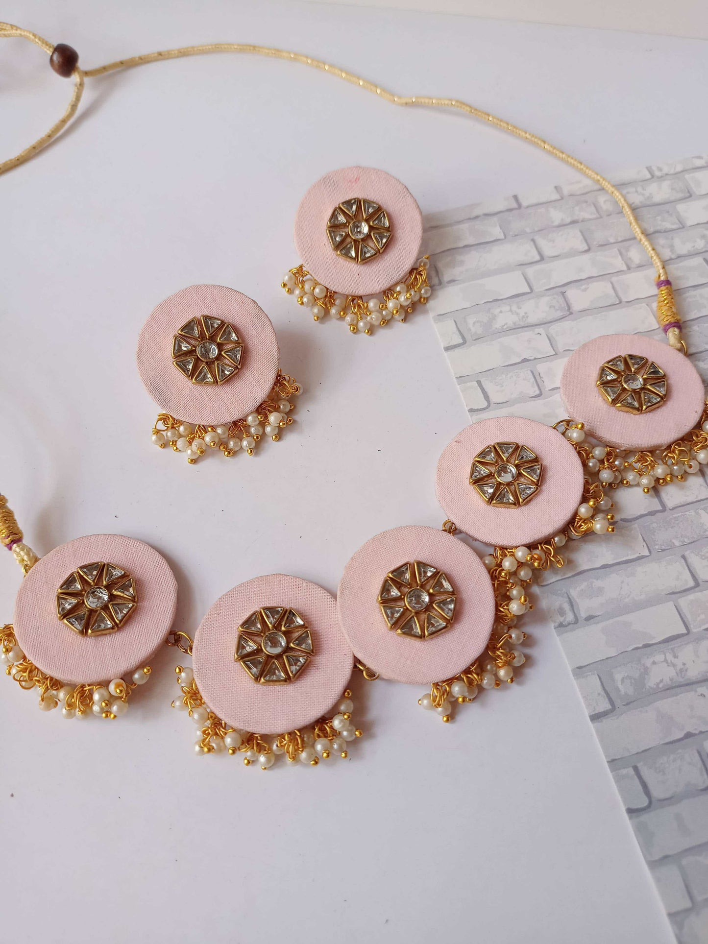 Pink round choker necklace with white beads and kundan on white backdrop