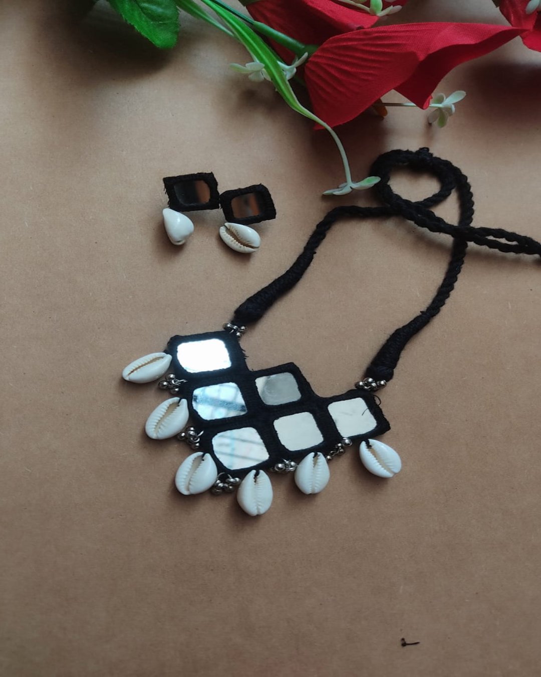 Black and white mirror necklace with sea shells on brown backdrop