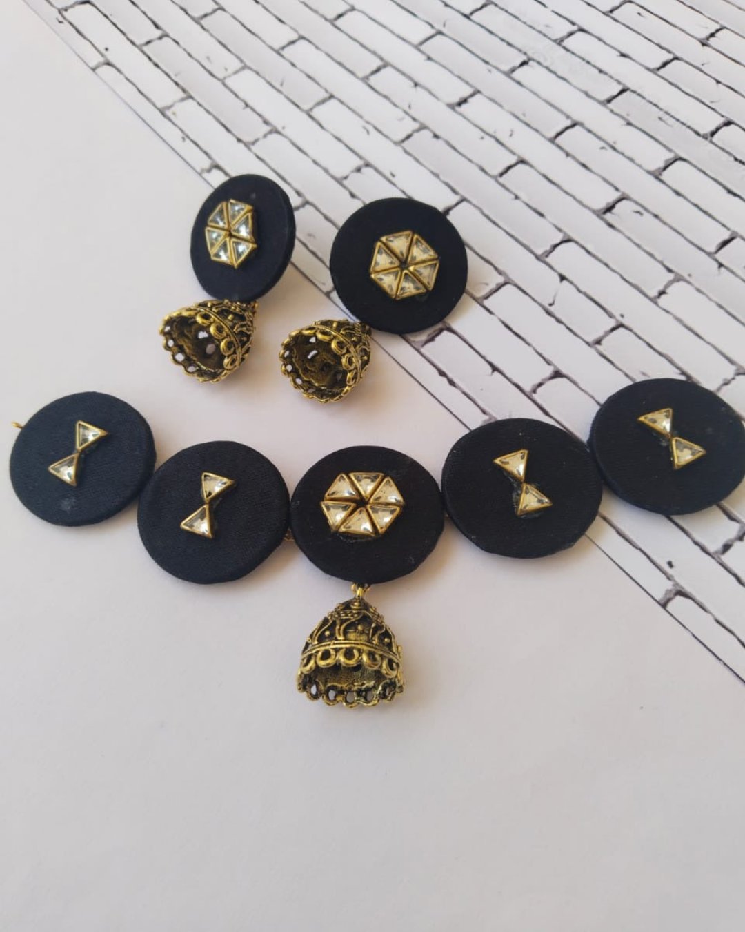 Black round choker necklace with kundan details and matching earrings on white backdrop