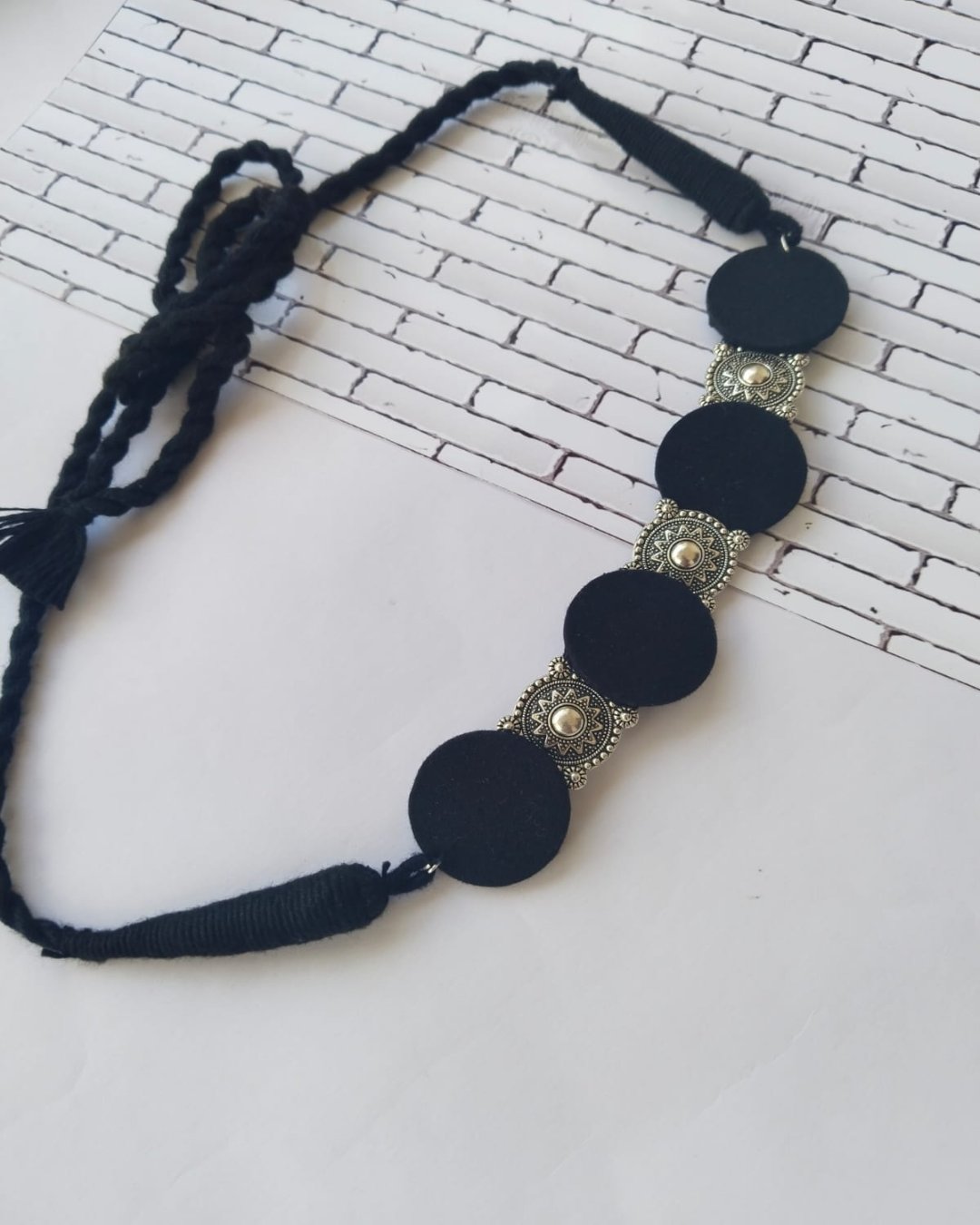 Black choker necklace with round charms in silver and black on white backdrop