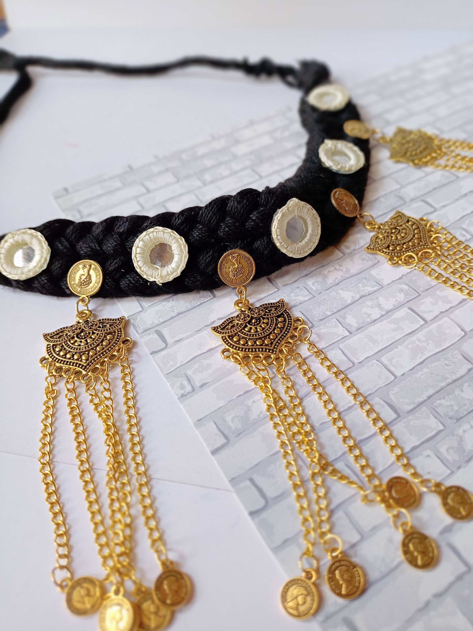 Black threads knitted choker wth golden latkan and mirrors on white backdrop