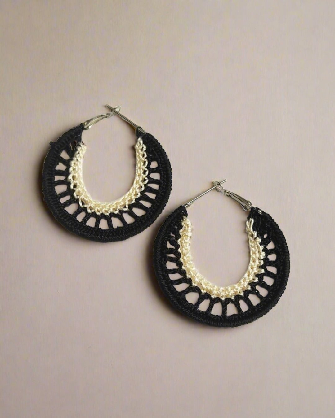 Black and white crochet hoops earrings on white grey backdrop