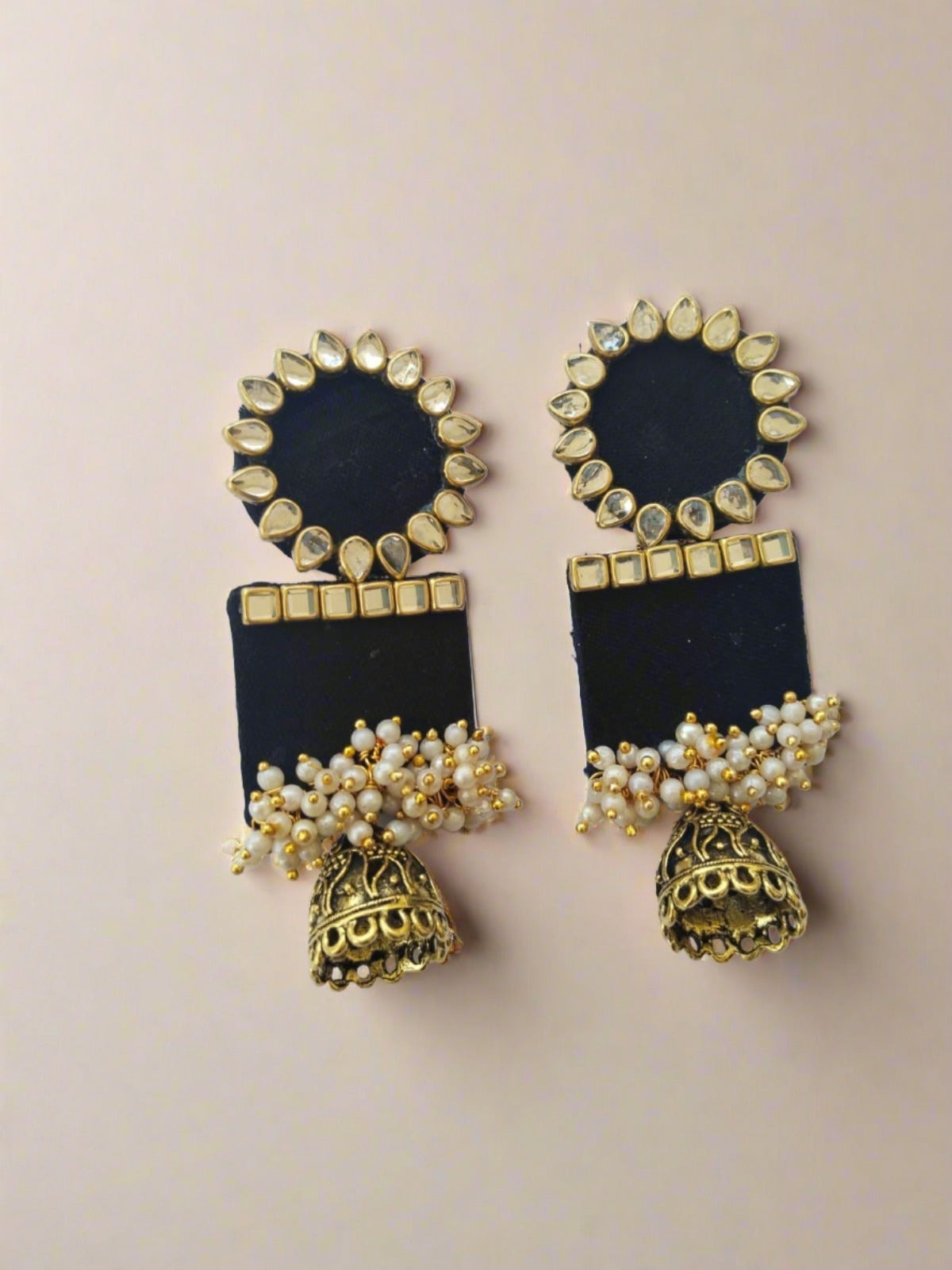 Black rectangular jhumka with white and golden beads on white grey backdrop