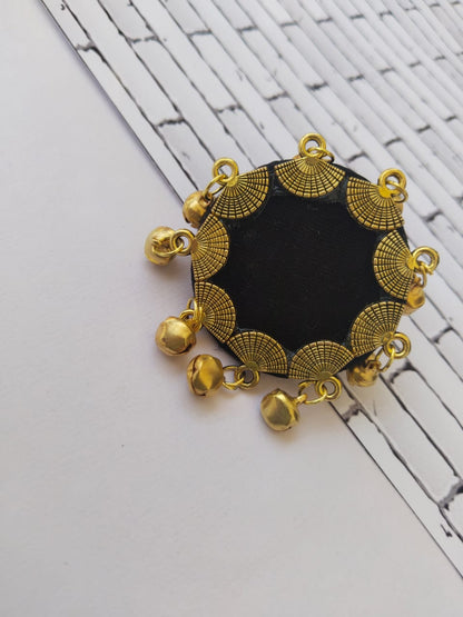 Black round finger ring with golden border and ghungroo on white grey backdrop