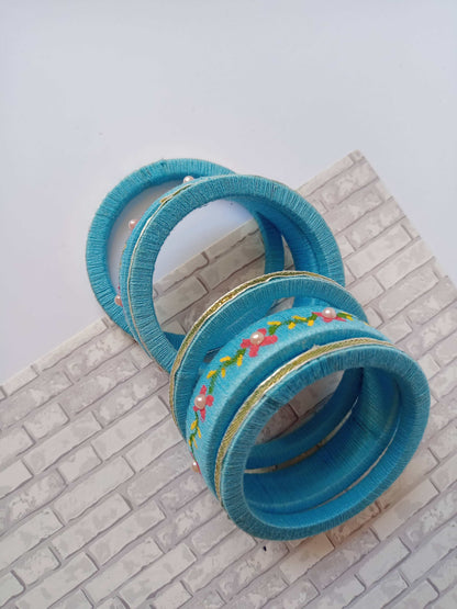 Light blue embroidered fabric bangles set on white grey backdrop