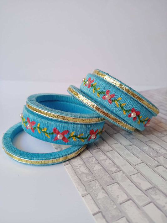 Light blue embroidered fabric bangles set on white grey backdrop
