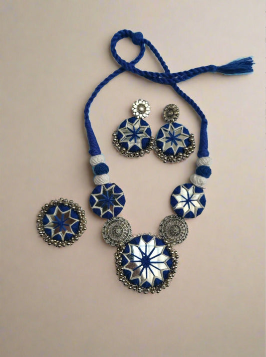 Blue necklace and earrings with mirror and silver charms on white backdrop