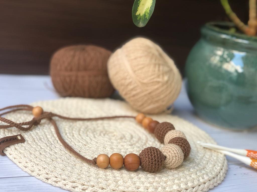 Brown and light brown crochet round necklace on white crochet base with threads in backdrop