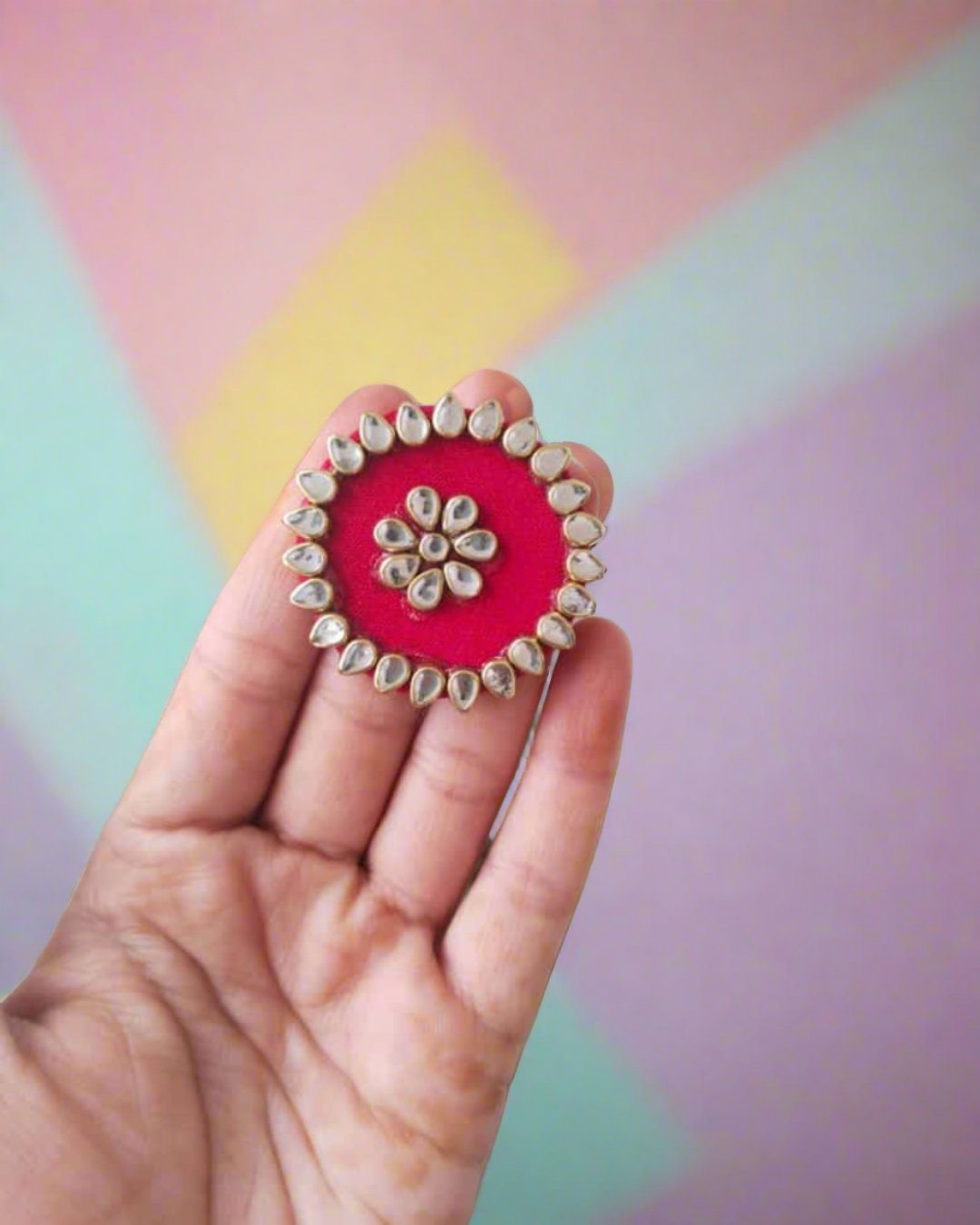 Palm wearing red round finger ring with kundan border on white backdrop