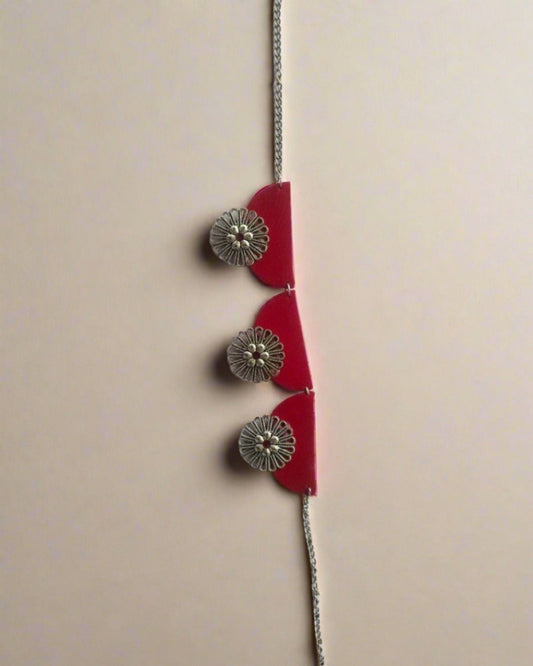 Red semi round choker necklace with floral silver charms on white backdrop