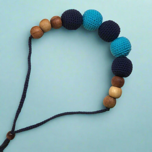 Dark and light blue crochet round beaded choker necklace on book backdrop