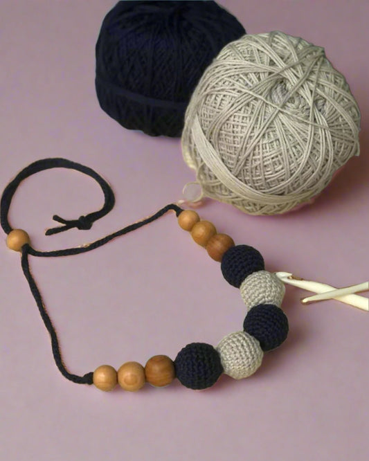 Dark blue and grey crochet round beaded choker necklace on beige backdrop