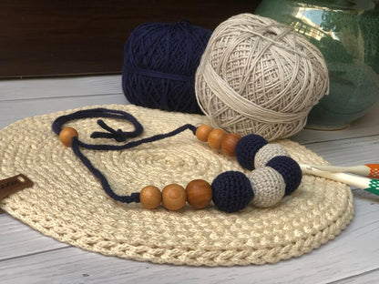 Dark blue and beige crochet round necklace with wooden beads on white crochet base