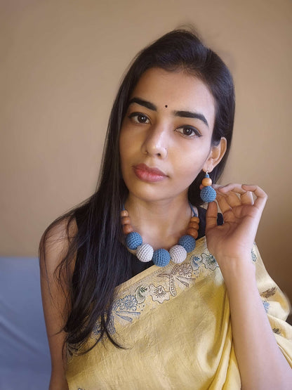 Indian woman in yellow saree wearing Dark blue and grey crochet round beaded choker necklace and earrings on white backdrop