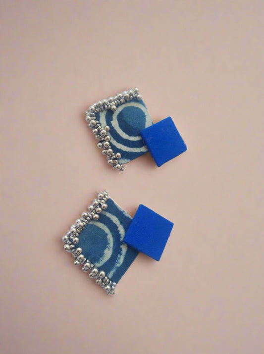 Dark blue and printed indigo blue earrings with silver beads on white backdrop