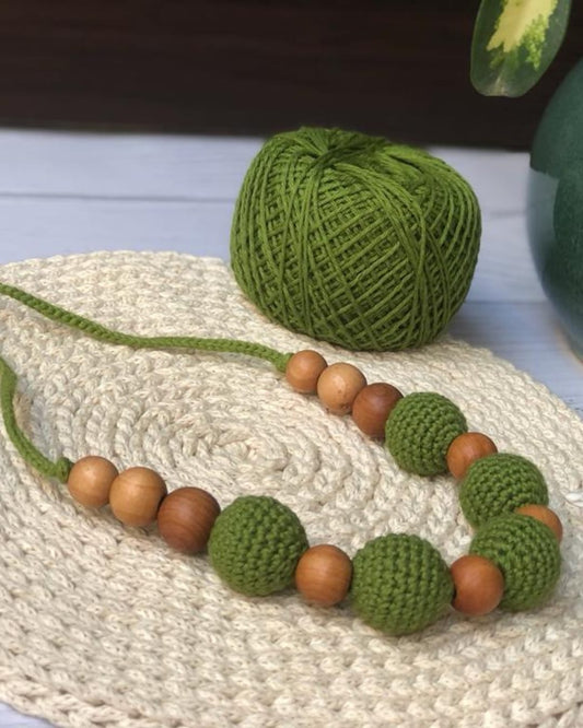 Dark green crochet necklace with brown beads on white crochet base