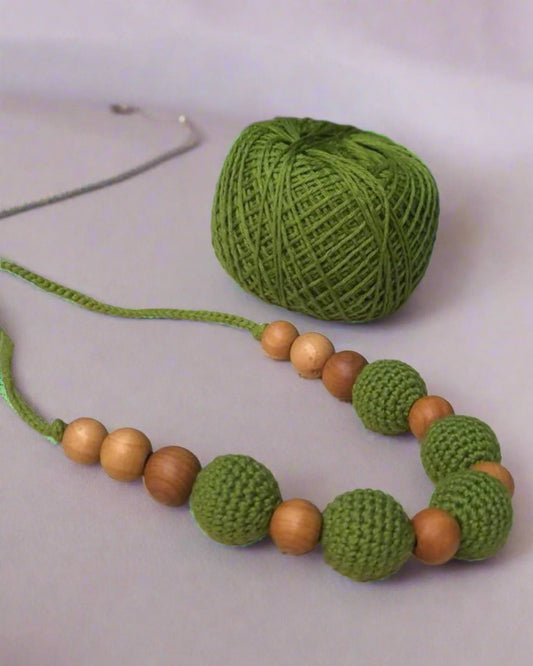 Dark green crochet necklace with brown beads on white crochet base