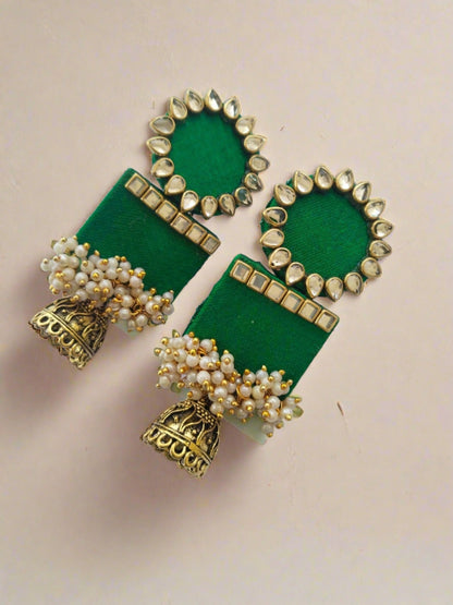 Dark green rectangular jhumka with white and golden beads on white grey backdrop