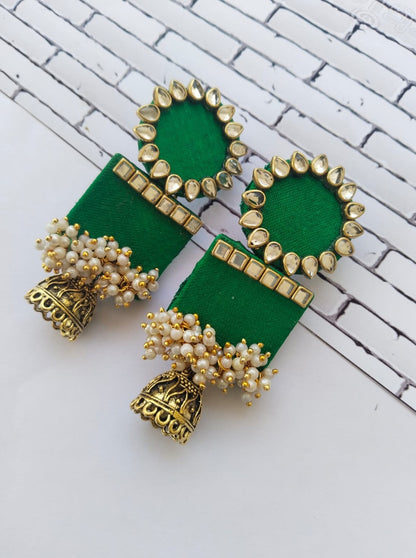 Dark green rectangular jhumka with white and golden beads on white grey backdrop