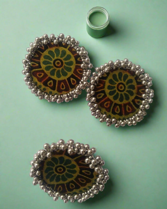 Green ajrakh print round finger ring and earrings with silver beads border on white grey backdrop