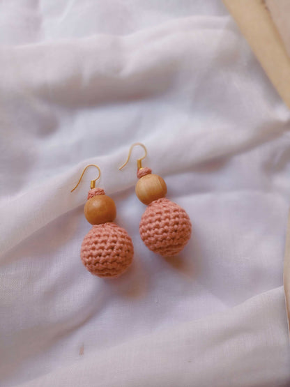 Pastel peach and light pink crochet round beaded earrings on white backdrop