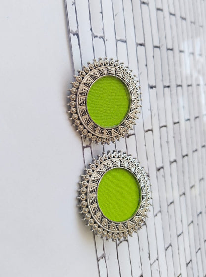 Lime green round studs earrings with silver chain border on white backdrop
