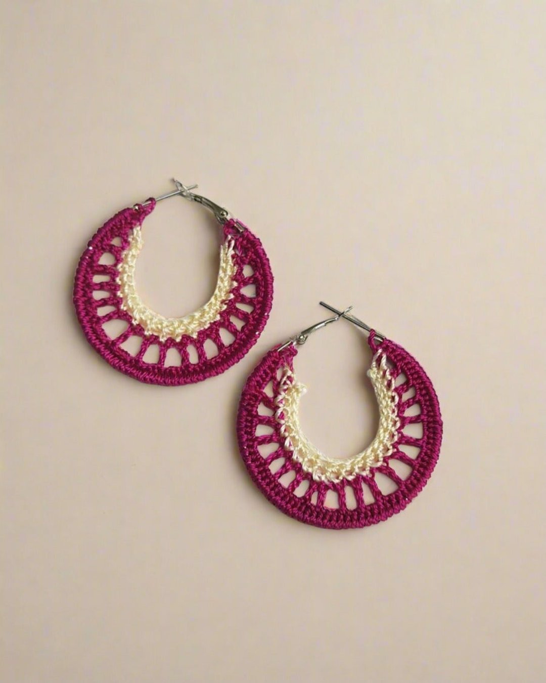 Magenta pink and beige crochet hoops earrings on white grey backdrop
