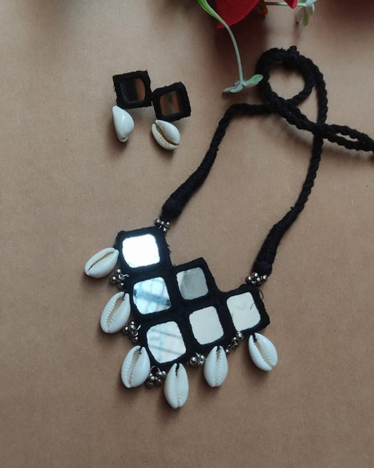 Black and white mirror necklace with sea shells on brown backdrop