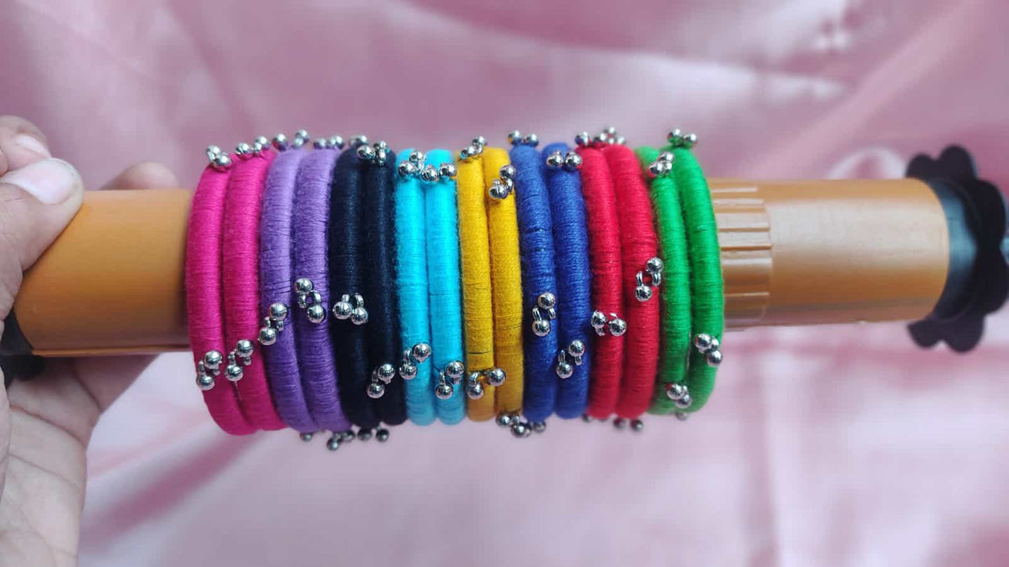 Multi color bangles on wooden stick on a pink backdrop